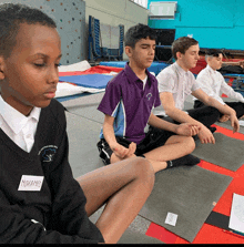 a boy with a name tag that says mohamd sits on a mat