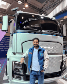 a man stands in front of a white truck with the word ford on the front