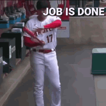 a baseball player is standing in a dugout with a sign that says `` job is done '' behind him .