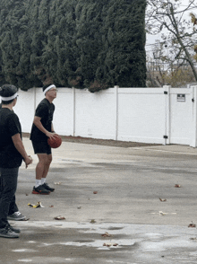 a man holding a basketball in front of a white fence with a sign that says no parking