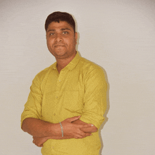 a man in a yellow shirt has his arms crossed and a bracelet on his wrist