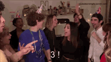 a group of people wearing party hats are celebrating a birthday with the number 3