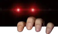 a person 's fingers are sticking out of a hole in a dark room with red lights behind them