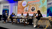 a group of women sit at a table in front of a sign that says ' asiva ' on it