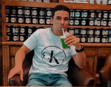 a man is sitting in a chair drinking a green beverage through a straw .