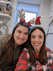 two women wearing reindeer antlers and santa hats are posing for a picture