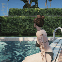 a woman with a tattoo on her arm sits on the edge of a pool