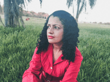 a woman in a red shirt sits on the grass