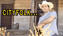 a man in a cowboy hat is standing in front of a building with the words cityfolk written above him