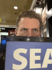 a man holds up a sign that says sea in front of his face