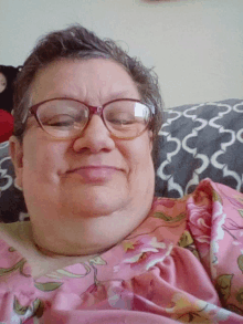 a woman wearing glasses and a pink floral dress smiles for the camera