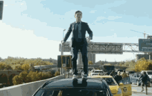 a man in a suit and tie stands on top of a car