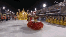 a woman in a red and gold dress is dancing in front of a crowd with the words carne uo on the bottom left