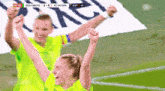 two female soccer players are celebrating with their arms in the air during a game between wolfsburg and fc bayern