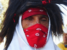 a man wearing a red bandana around his face and a wig .