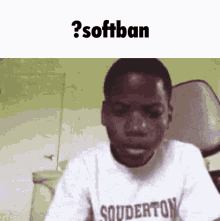 a young man wearing a squiderton shirt is sitting in a chair