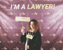 a woman holds up a sign that says i 'm a lawyer