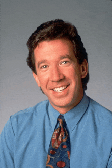 a man in a blue shirt and tie is smiling for the camera