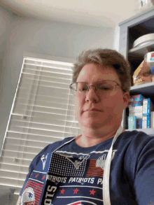 a woman wearing a patriots shirt and apron looks at the camera