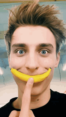 a young man with a banana in his mouth making a smiley face