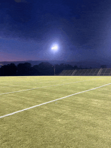 a football field with a stadium in the background at night