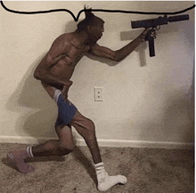 a shirtless man holding a gun in a room