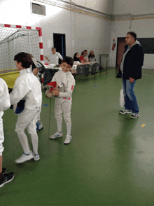 a boy holding a sword in a gym with a man standing behind him