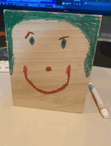 a child 's drawing of a smiley face on a wooden block