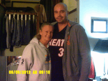 a man wearing a heat jersey stands next to a woman wearing a number 2 sweatshirt