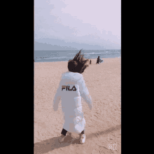 a person wearing a fila jacket is standing on a beach