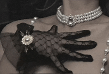 a woman wearing a pearl necklace and a black glove