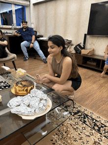 a woman sits on a table with a cake on it