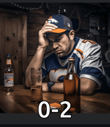 a man in a broncos jersey sits at a table with a bottle of budweiser