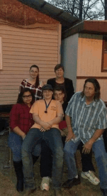 a group of people posing for a picture including a boy wearing an orange shirt that says texas on it