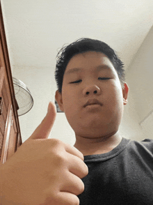 a young boy gives a thumbs up sign with his eyes closed