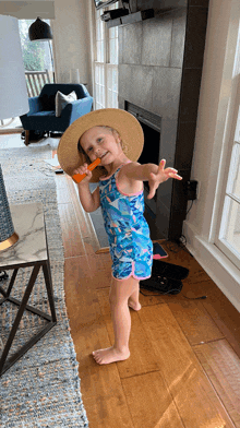 a little girl is wearing a straw hat and holding an orange stick in her hand