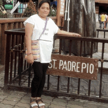 a woman is standing in front of a sign that says st padre pio