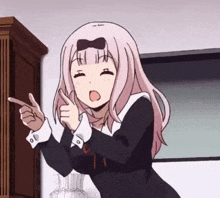 a girl with pink hair is pointing her finger at something .