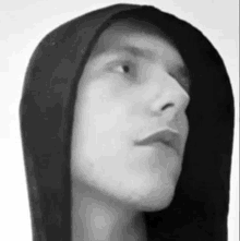 a black and white photo of a man wearing a black hoodie .