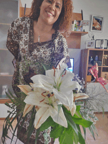 a woman is holding a bouquet of white flowers in her living room