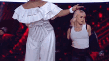 a woman in a white tank top stands next to a woman in a white corset