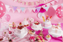 a table with cakes and balloons with a banner that says happy birthday