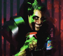 a man with green paint on his face holds a bottle of mtn dew