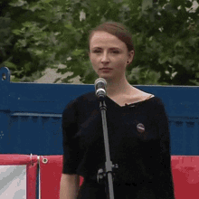 a woman stands in front of a microphone with a button on her shirt that says i voted for trump