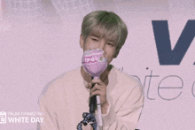 a man in a white sweater is holding a pink lollipop in front of a microphone ..