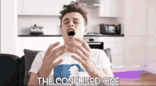 a young man is sitting on a couch with his mouth open and the words the confused one written on the bottom .