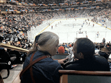 a man and a woman sit in a stadium watching a hockey game sponsored by coca cola