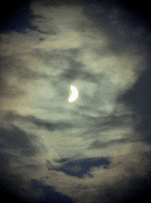 a partial eclipse of the sun is visible in a cloudy sky