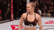 a woman is standing in a boxing ring with the words `` do n't cry '' written on her face .