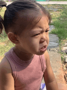 a little girl in a pink tank top is making a face